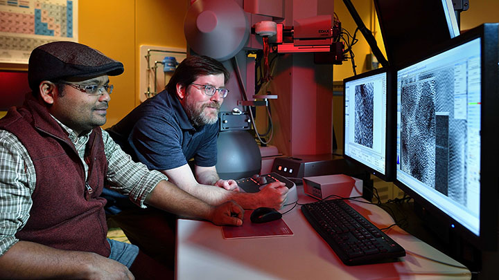 Two researchers looking at equipment screen